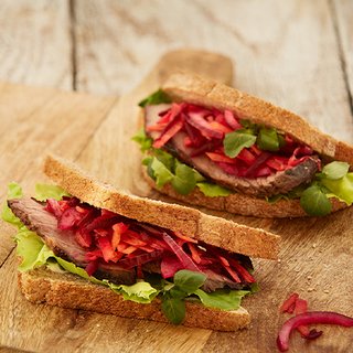 A sandwich cut in half, filled with beef, lettuce, beetroot and red onion.
