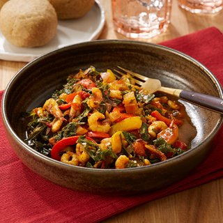 A bowl of kale riro, a spiced stew made with prawns, kale and peppers, served with a portion of fufu