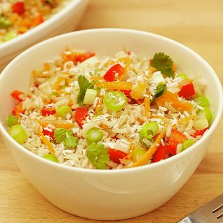A colourful bowl of rice mixed with pepper, carrot and spring onion