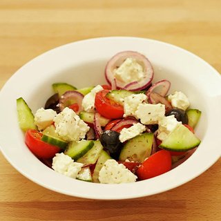 A Greek-style salad with cucumber, olives, tomatoes, onion and crumbly cheese served in a bowl