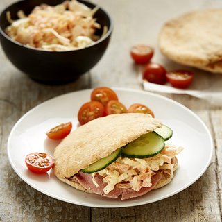 Ham and coleslaw pittas finished off with slices of cucumber and served with halved cherry tomatoes