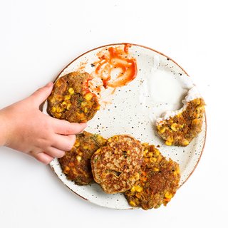 4 golden sweet potato and sweetcorn fritters on a plate with mint yoghurt dip