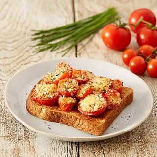 Grilled tomatoes with melted cheese on a slice of toast