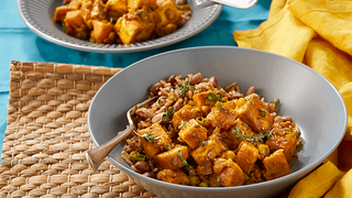 Chunks of fried, curried tofu and sweet potato, served in a bowl with mixed rice and kidney beans.