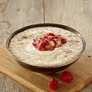 A bowl of banana porridge topped with mashed raspberries