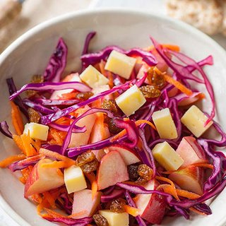 Carrot, red cabbage, red onion, apple and cheese salad in a bowl