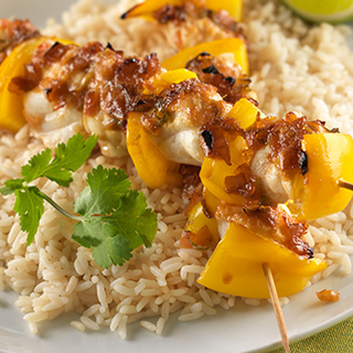 Chunks of grilled, glazed pepper and fish on a bed of rice