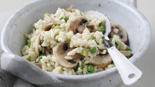 Mushroom risotto with peas served in a bowl with a spoon.