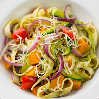 A portion of tagliatelle mixed with roasted red peppper, butternut squash, onion and courgette, topped with grated cheese