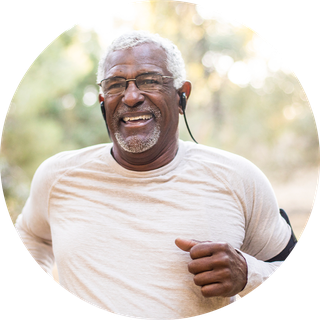 Older man outside running with headphones in his ears and a mobile phone strapped to his arm