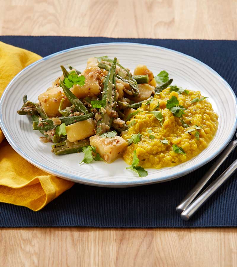A plate of curried sliced okra and cubed potato, served with dhal