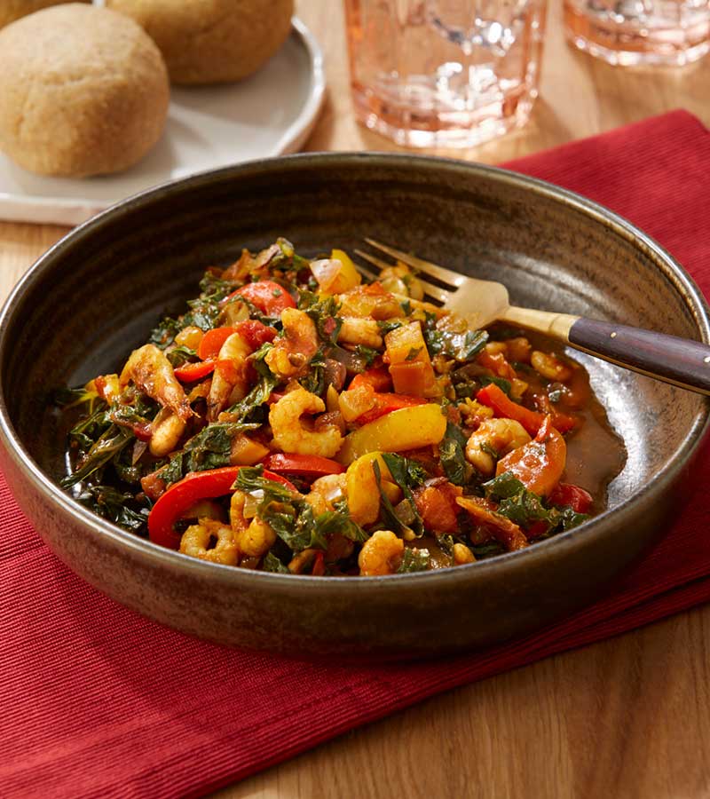 A bowl of kale riro, a spiced stew made with prawns, kale and peppers, served with a portion of fufu