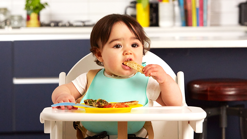 baby in a highchair eating finger food